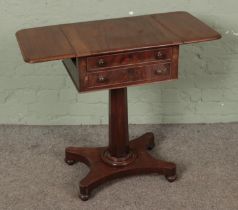 Regency mahogany teapoy having two facing drawers and supported on a pedestal quatraform base.