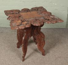 An extensively carved mahogany occasional table with folding base. Height 63cm, Top dimensions