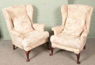 A pair of upholstered wingback armchairs with floral decoration.