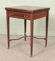 An Edwardian mahogany envelope card table, with drawer to the front, baize interior and banded