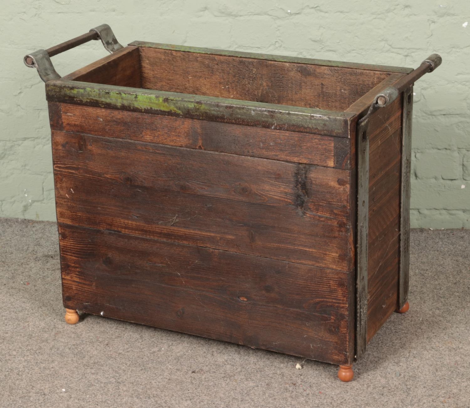A panelled log basket with metal surround, raised on small turned feet. Height: 64cm, Width: 84cm,