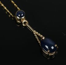 A 9ct gold and sapphire pendant on chain set with two cabochon stones. Total weight 2.1g.