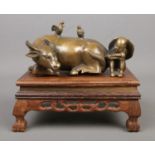 A Chinese bronze sculpture formed as a seated man next to a recumbent water buffalo. Bearing