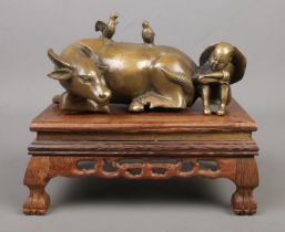 A Chinese bronze sculpture formed as a seated man next to a recumbent water buffalo. Bearing