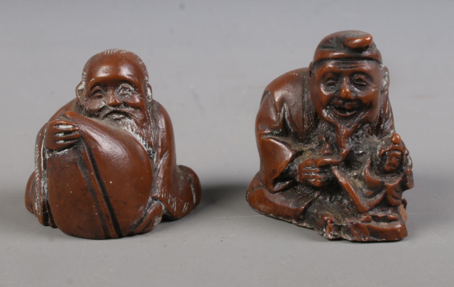 Two Japanese carved hardwood netsukes formed as a gentleman crafting a doll and a gentleman