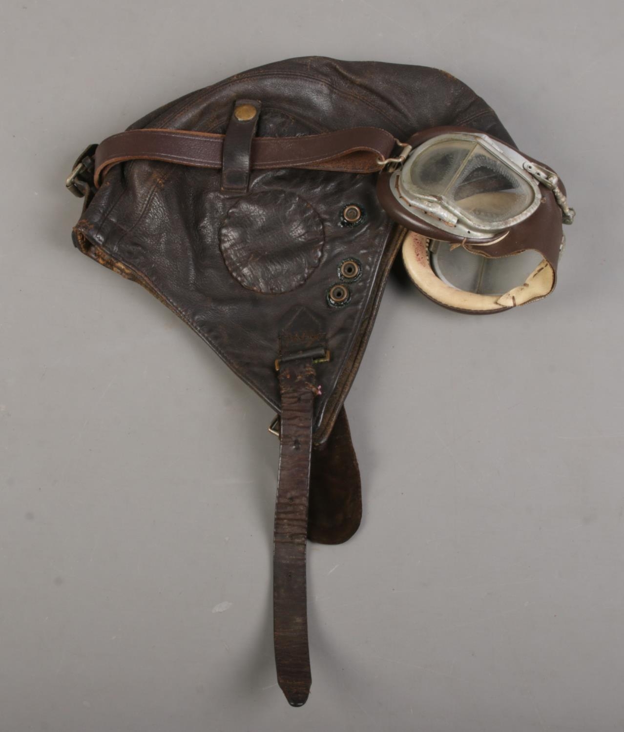A WWII period leather aviation helmet and goggles.