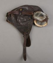 A WWII period leather aviation helmet and goggles.