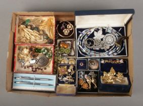 A tray of assorted vintage costume jewellery and accessories to include gilt floral brooches,