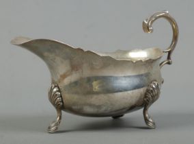A George VI silver sauceboat, raised on three shell and hoof feet. Assayed London, 1939 by Edward
