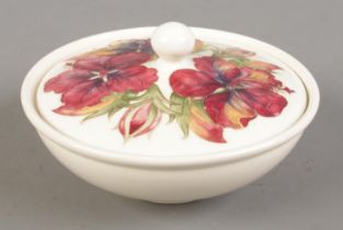 A Moorcroft pottery lidded bowl decorated in the Hibiscus pattern. Diameter 17cm.