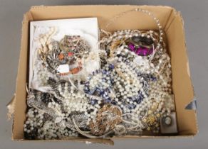 A box of costume jewellery. Includes beads, bangles, brooches, etc.