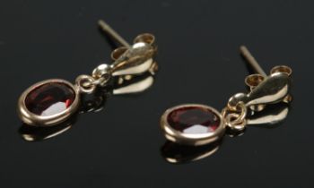 A pair of small 9ct gold drop earrings set with garnets. Total weight 0.6g.