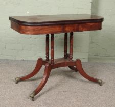 A Victorian mahogany fold over table. Raised on brass lion paw castors.