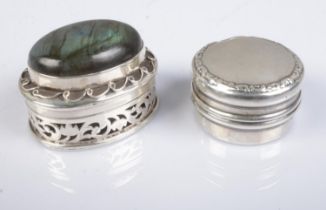 Two silver pill boxes; one pierced floral and scrolled detailing and mounted with large polished