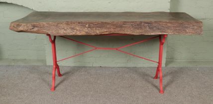 A large chunky live/waney edge table with cast iron base having B G Tournus on either side of