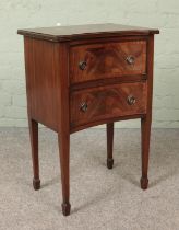 A small two drawer mahogany chest raised on tapering supports. Piece of veneer lacking to top.
