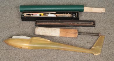 A fiberglass glider shell along with model plane building kit, spare balsa wood and cricket bat.