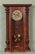 A mahogany Vienna style wall clock featuring roman numeral dial. With key.