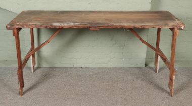 A large wooden tressle table with folding legs. (86cm x 183cm x 66cm)