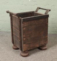 A panelled log basket featuring metal surround and handles on bun feet. Hx62cm Wx58cm Dx38cm