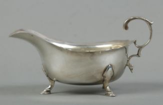 An early Twentieth Century silver cream jug, with frilled edge and raised on three hoof feet.