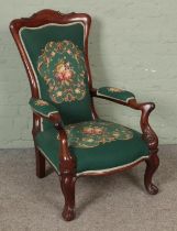 A Victorian mahogany upholstered armchair with scrolling frame.