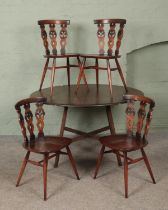 An Ercol drop leaf dining table, accompanied by four dining chairs with triple 'Fleur de Lys' splat.