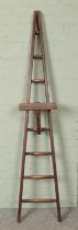 A slender set of wooden ladders of A-Frame form, possibly for fruit picking. With eight rungs and