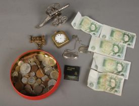 A tin of coins and collectables. Includes silver plate desk cannon, banknotes, silver Sherry