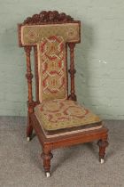 A Victorian walnut heavily carved prayer dieu chair.