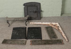 A collection of cast iron fire accessories to include decorative plaques and painted stove door.