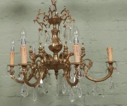 An ornate six branch brass chandelier with glass droplets. Drop (not including chain) 58cm, Width