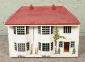 A painted two storey dolls house with tinplate sliding front.