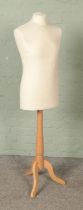 A modern polystyrene dress form mannequin raised on turned wooden stand.