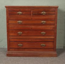 A mahogany two over three chest of drawers featuring carved bands and brass handles to drawers.