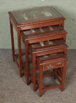 An oriental nest of four tables with smallest featuring central drawer.
