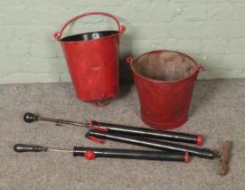 Two vintage red painted fire buckets along with three painted water pumps.