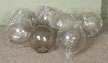 Seven clear plexiglass light shades in globe form.