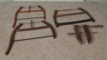 Three antique frame saws along with a wooden clamp.