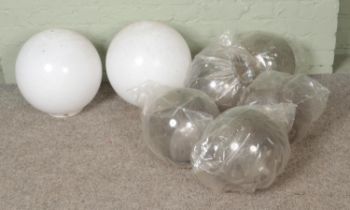 Seven plexiglass light shades in globe form to include two opaque white examples.