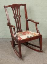 An oak rocking chair with upholstered drop seat.