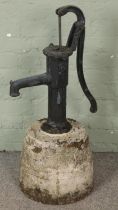 A cast iron water pump raised on concrete base. (90cm)