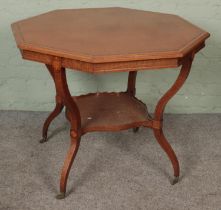 A large Edwardian mahogany inlaid table with shaped legs united by a lower tier shelf on brass