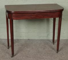 A George III mahogany fold over inlaid tea table on brass castors. Hx77cm Wx90cm Dx44cm