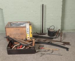 A box and a crate of assorted tools to include saws, hay knife, axe, laser level, etc.