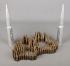 A belt of LC57 machine gun cartridges along with two inert artillery rounds.