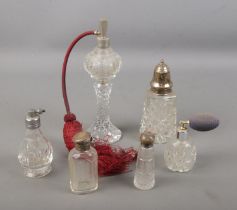 A collection of cut glass atomisers and scent bottles including a silver topped sugar caster. Silver