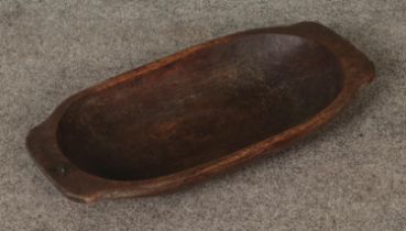 A wooden dough bowl approx. 64cm long. Woodworm.
