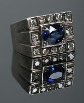 A silver tank ring set with a central sapphire coloured stone and a border of twelve diamonds.