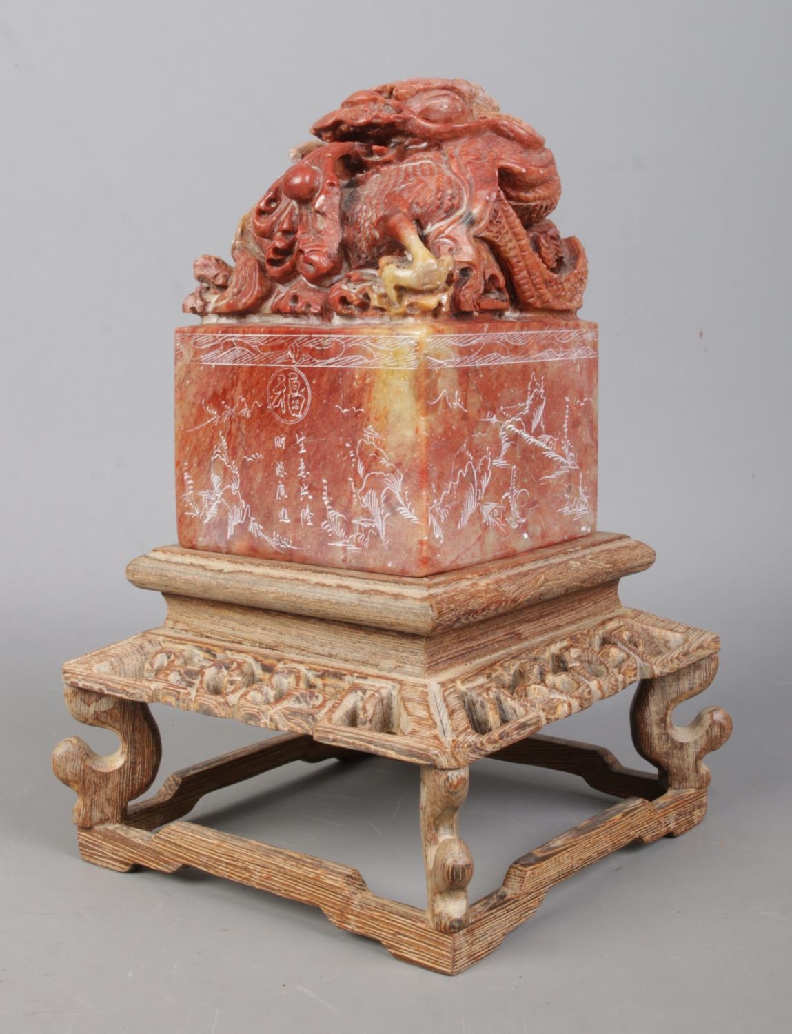 A Chinese carved soapstone seal raised on carved wooden stand. The seal surmounted with a Qilin